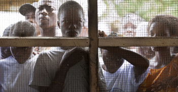 Young Liberians listen outside a women’s peace hut in Totoa, Bong County, Liberia. 7 March 2011. Photo Source: UN Photo/Staton Winter.