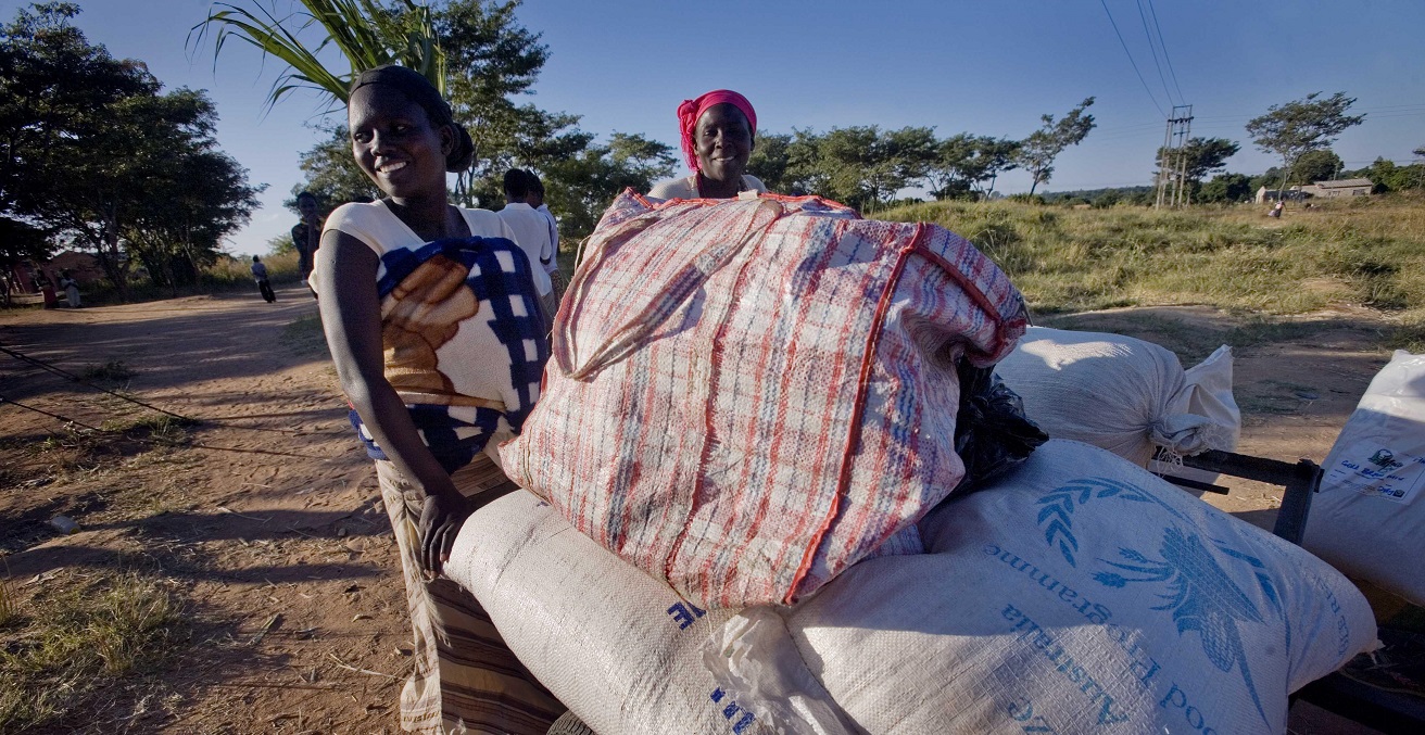 Women carry their village's food aid from Australia in a cart.