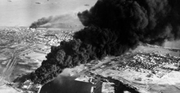 Smoke rises from oil tanks beside the Suez Canal hit during the initial Anglo-French assault on Port Said, 5 November 1956. Photograph MH 23509 from the collections of the Imperial War Museums