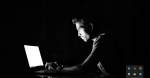 Man sits at a computer in the dark.  Source: https://bit.ly/332qUNG