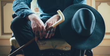 Man sitting on chair holding hat and cane. Source: https://pxhere.com/en/photo/1020358