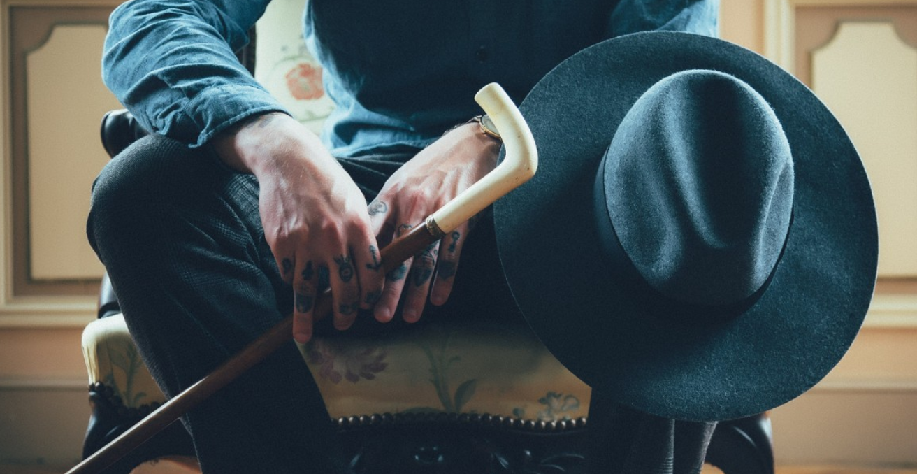 Man sitting on chair holding hat and cane. Source: https://pxhere.com/en/photo/1020358