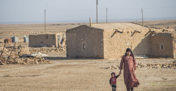 A man and child walkng across a sandy landscape in Syria. Source: Peter Biro https://bit.ly/2WHtzdQ