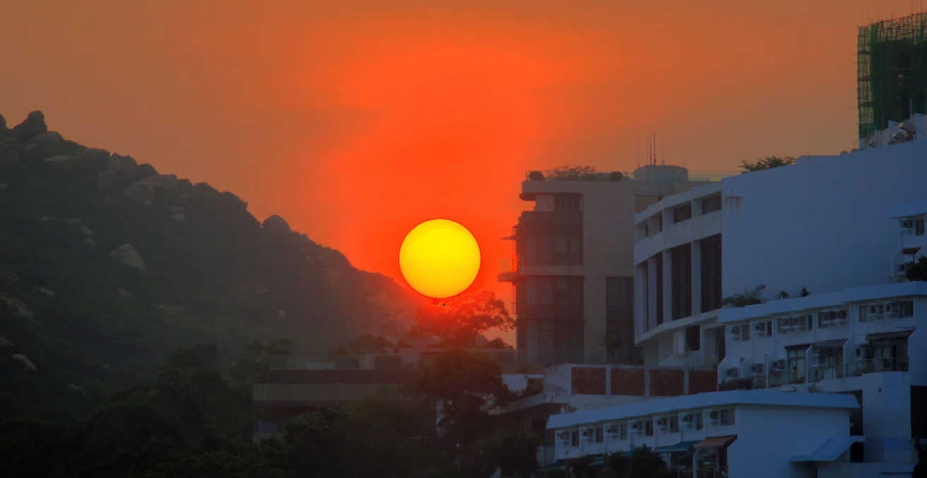 Close-up shot of a sunset over Hong Kong, including the city, mountains and bay area. Source: Yinan Chan https://bit.ly/35yA5IR