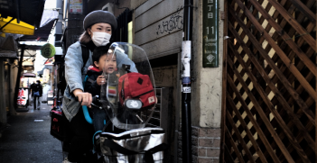 People riding a motorbike through the streets of Japan. Source: John Doe https://bit.ly/3sAdy84